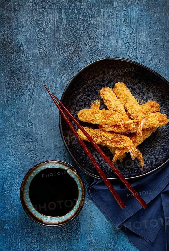 Shrimp in tempura, deep fried, on a black plate, with soy sauce, close-up, top view, no people