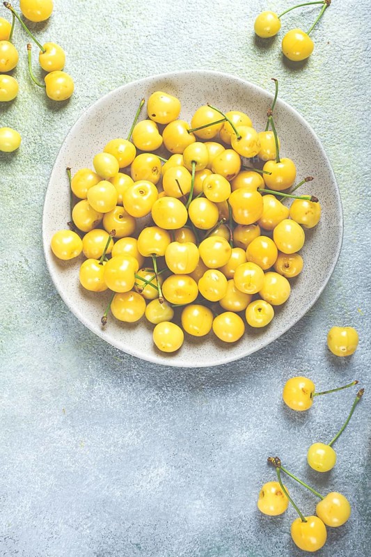 Yellow cherry, cherry berry, scattered on a plate, top view, no people