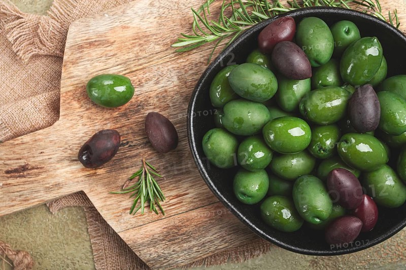 Chalkidiki olives, classic Greek green olives, in a bowl on a cutting board, top view, without people
