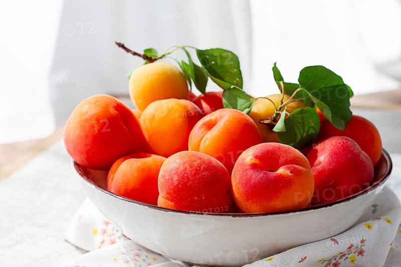 Fresh apricots in a bowl, on a bright table, natural light, top view, no people