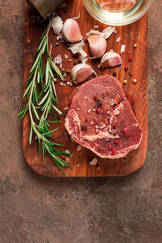 Fresh, raw rib eye steak, on a chopping board, top view, no people