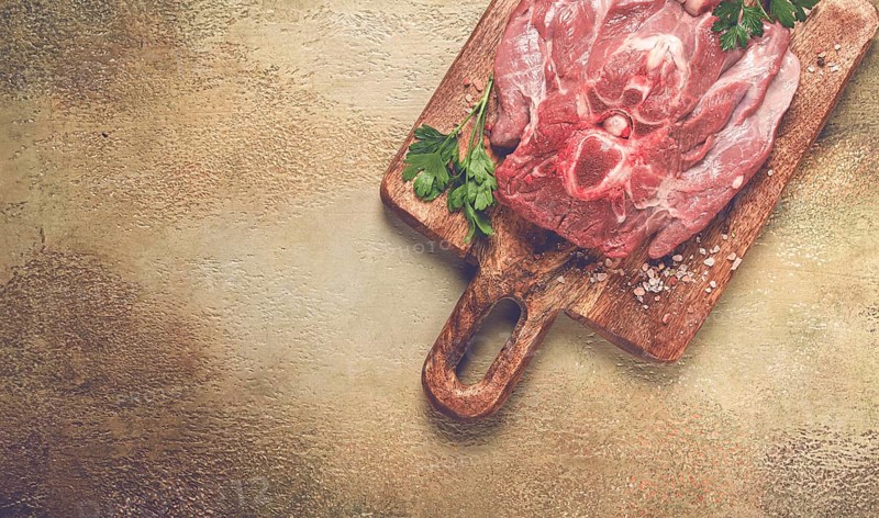 Raw steak, veal neck on the bone, fresh meat, on a cutting board, with spices, top view, without people