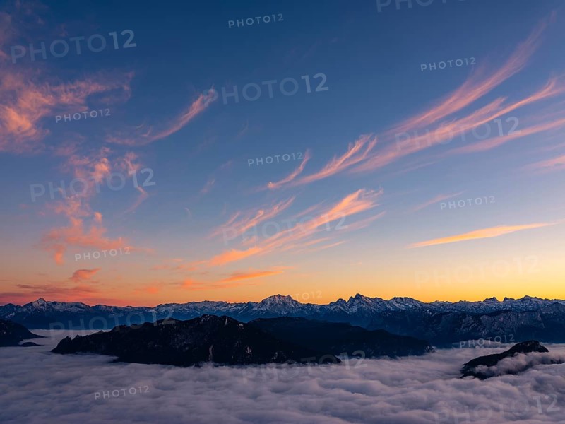 Red-colored plume clouds over the Berchtesgaden Alps at dusk, fog in the valley, Hochstaufen, Chiemgau Alps, Upper Bavaria, Germany