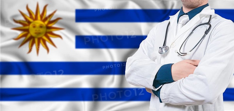 Uruguay healthcare concept. Male doctor on Uruguay flag. Doctor with crossed arms on Uruguay flag