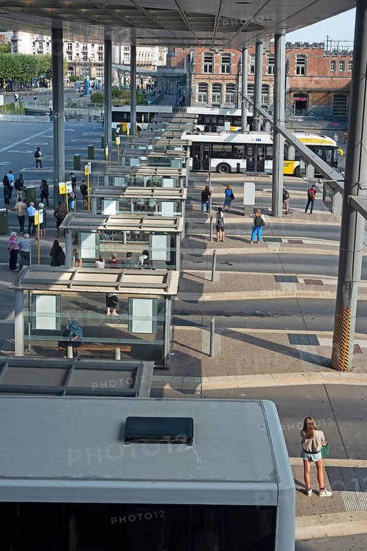 Commuters waiting for transit buses at bus stop of public transport company De Lijn at train station Gent-Sint-Pieters, Ghent, East Flanders, Belgium