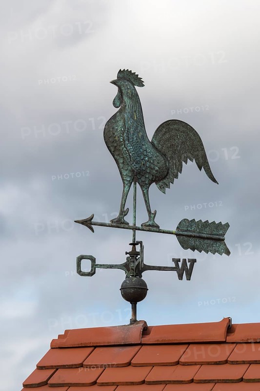 Metal weather vane with rooster on a tiled roof against cloudy sky, Baden-Württemberg, Germany