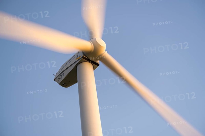 Wind turbine with rotating blades moving against a clear sky, Baden-Württemberg, Germany