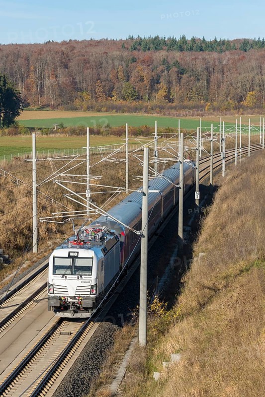 A passenger train travels through an autumnal landscape with fields and forests in the background, surrounded by overhead lines, new Stuttgart-Munich line, near Dornstadt, Swabian Jura, Baden-Württemberg, Germany