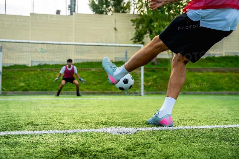 Soccer player preparing to kick a penalty shot towards the goal, with a vigilant goalkeeper in position, highlighting sports competition and the crucial moment of scoring