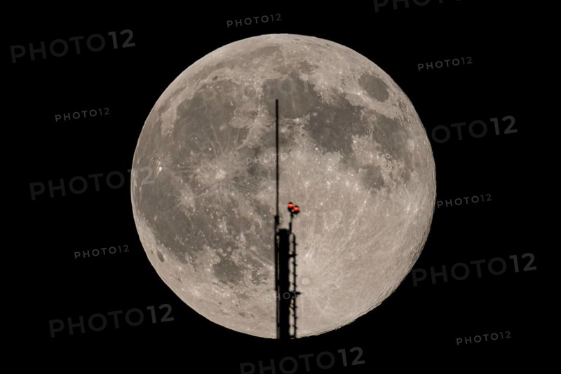 The full moon passes through the antenna on the roof of the European Central Bank (ECB), Frankfurt am Main, Hesse, Germany