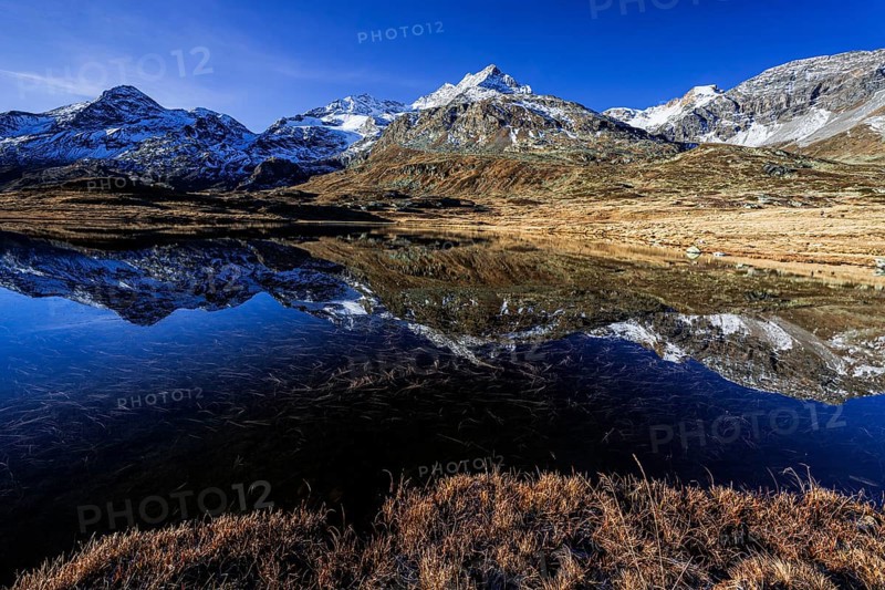 Mountains reflected in lake, morning light, autumn, sunny, Bernina Pass, Engadin, Switzerland