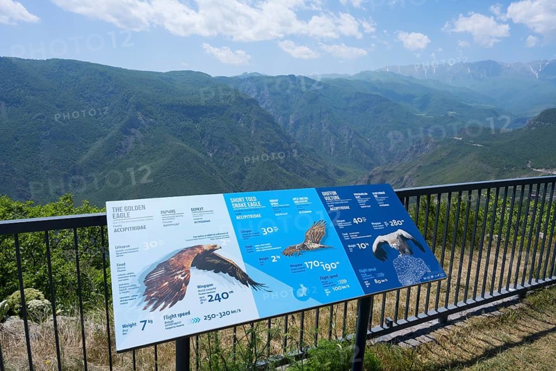 An observation deck with information boards about eagles shows a view of a mountainous landscape with blue sky, Halidzor, terrace at Wings of Tatev, Syunik province, Caucasus, Armenia