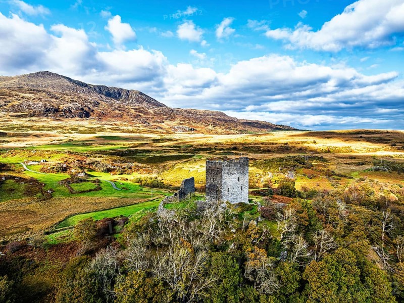 Autumn colours over Castell Dolwyddelan and Eryri Mountains from a drone, Snowdonia, Conwy County Borough, Wales, England, United Kingdom