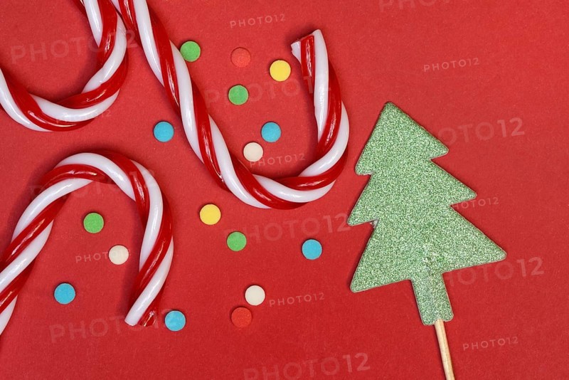 Candy canes and sugar confetti against red background, Christmas