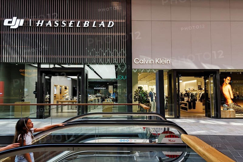 Shop window with logo, Hasselblad and Calvin Klein lettering, escalator, Westfield Überseequartier, modern shopping center, HafenCity, Hamburg, Germany