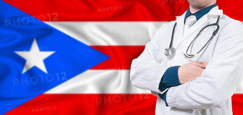 Puerto Rico healthcare concept. Male doctor on Puerto Rico flag. Doctor with crossed arms on Puerto Rico flag