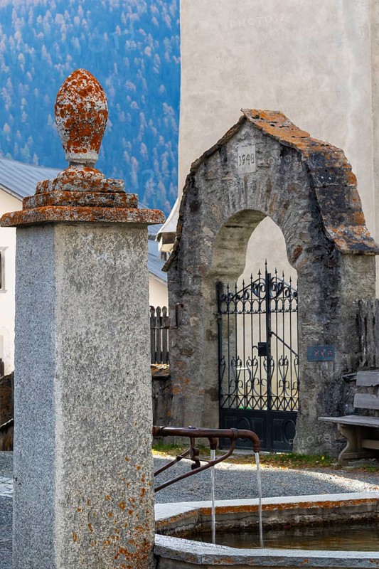 Village fountain in front of the entrance to the Firedhof, Tor, Guarda Engadin, Graubünden, Switzerland