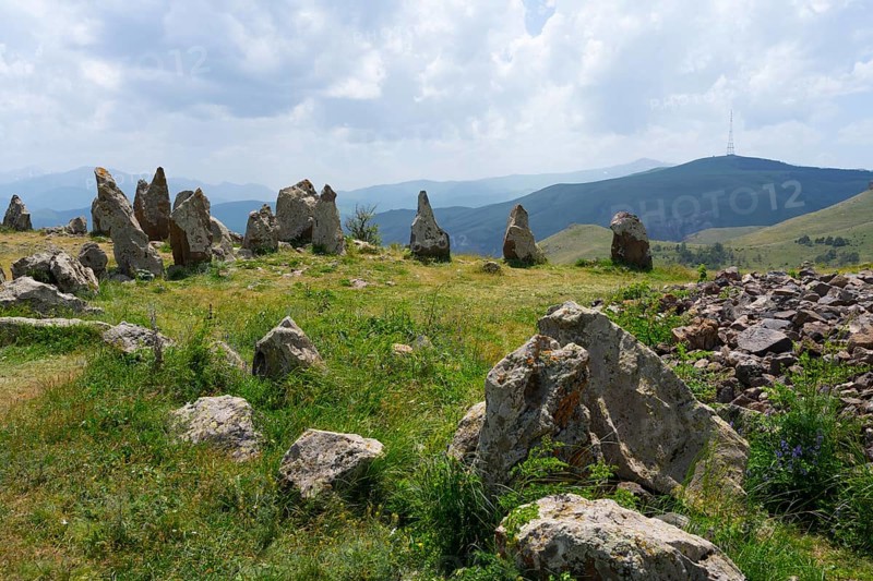 Stone formations in a meadow with a view of cloudy mountains, stone circle, megaliths, Zorats Karer, Karahundsch, Bronze Age burial ground, Sisian, Sisian, Sjunik province, historic Sangesur, Armenia