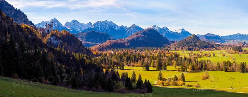 Panoramic picture, vast landscape with green fields, the distant Neuschwanstein Castle and majestic mountains, Schwangau near Füssen, Ostallgäu, Allgäu, Bavaria, Germany