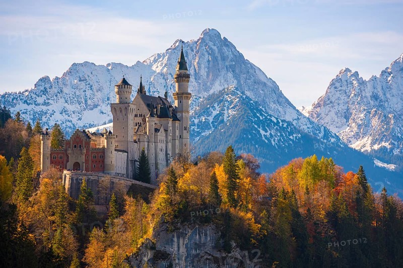 Neuschwanstein Castle is enthroned against an impressive mountain backdrop, surrounded by autumnal forests, Schwangau near Füssen, Ostallgäu, Allgäu, Bavaria, Germany