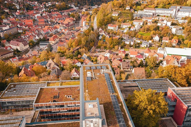 Panorama of a city in autumn colors, modern buildings with solar cells in the foreground, Calw District Office, Calw, Germany
