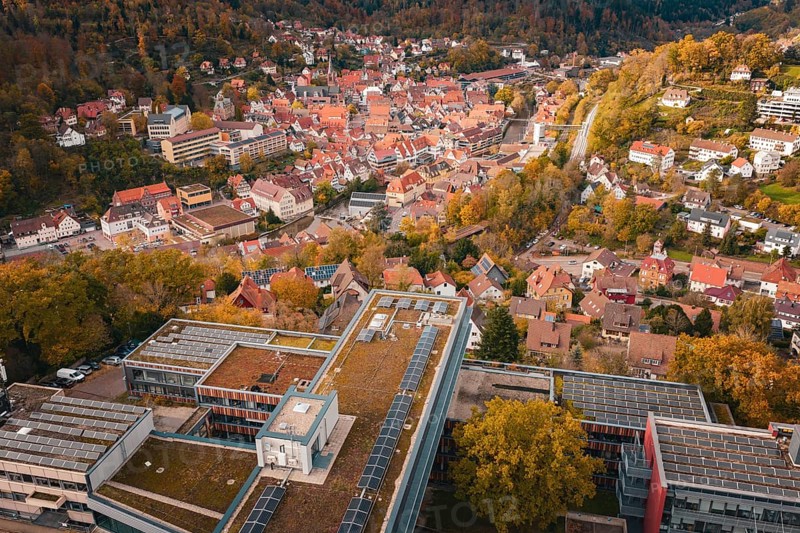 City view with various buildings, river and autumn trees from above, Calw District Office, Calw, Germany