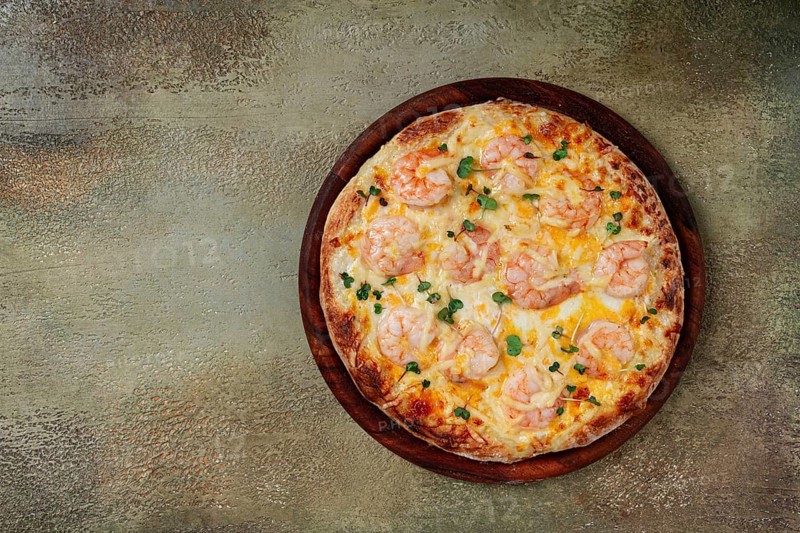 Four cheese pizza with shrimp and fresh microgreens, served on a wooden board, homemade, no people