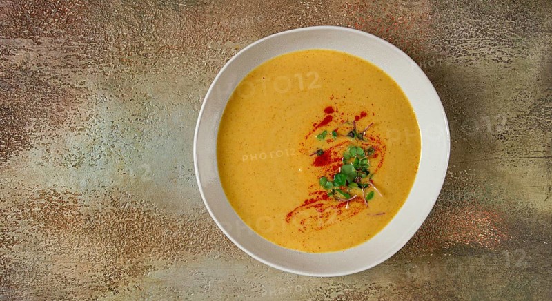 Pumpkin cream soup, in a white bowl on a textured background, top view, homemade, no people, rustic style