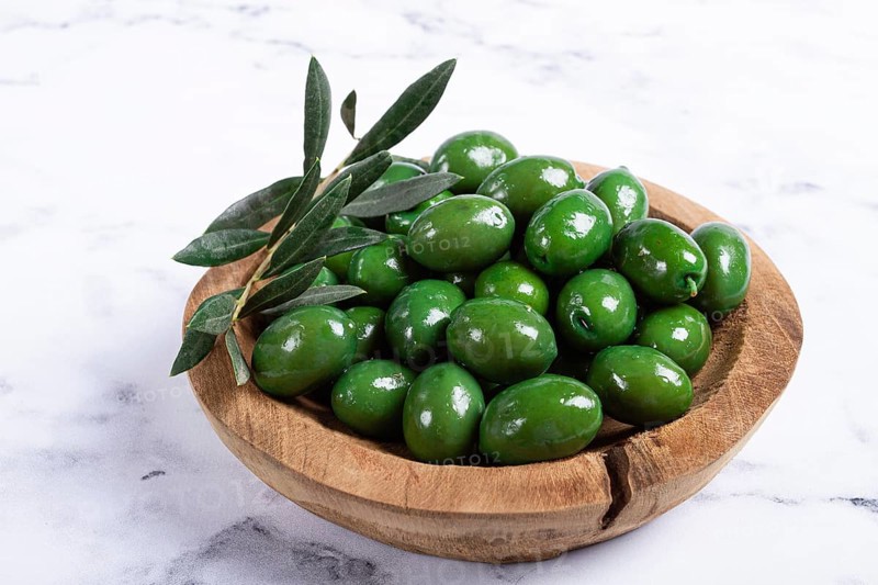 Halkidiki olives, classic Greek green olives, in a wooden bowl, on a marble table, no people
