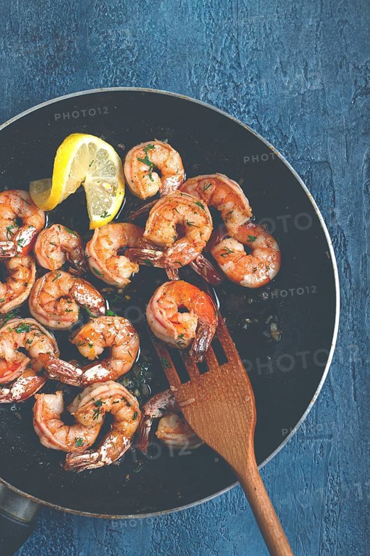 Fried tiger prawns, jumbo, in garlic sauce, in butter, with herbs, in a frying pan, homemade, no people