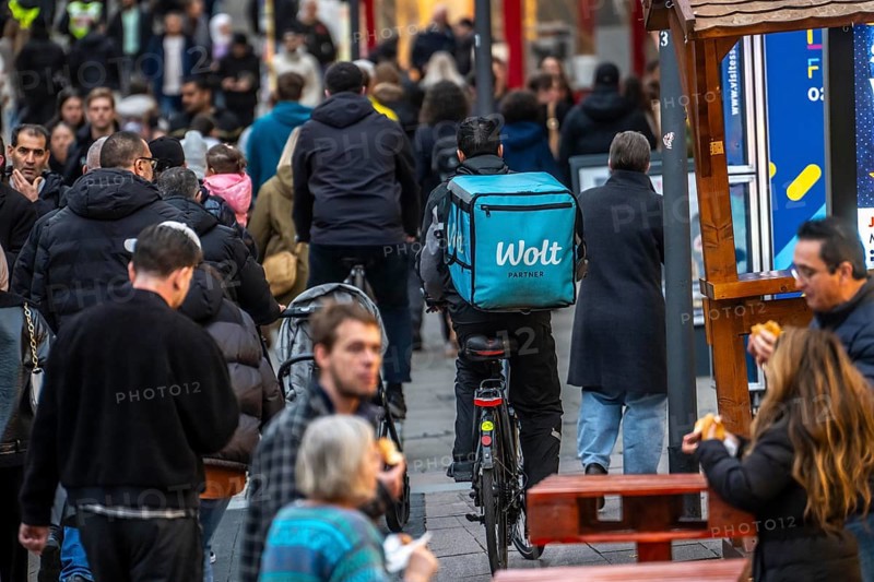 Full city center, shopping street, Kettwiger Straße pedestrian zone in Essen, bicycle courier from the Wolt delivery service crowds through the many people in front of the opening of the Christmas market, North Rhine-Westphalia, Germany