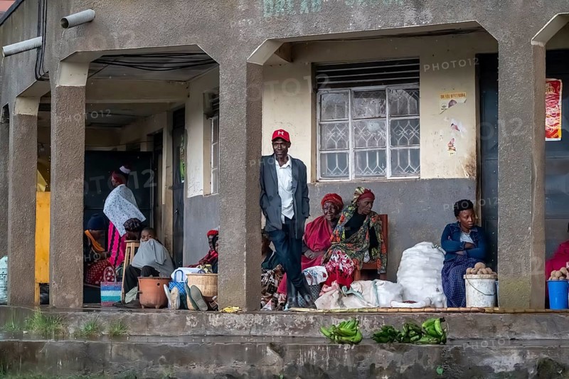 Street scene, people waiting outside houses for the rain to end selling vegetables, Kisoro, Uganda