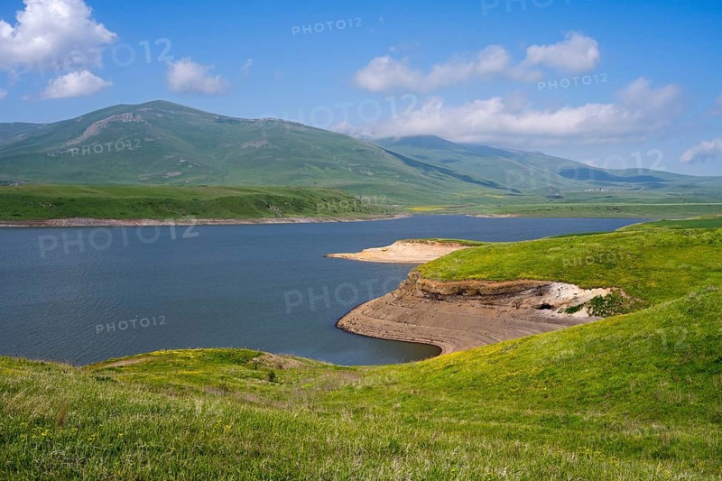 A calm lake surrounded by green hills and mountains under a blue sky with clouds, Spandaryan Reservoir, Spandarian, fed by Vorotan River, Vorotan, Syunik Province, Syunik, Armenia