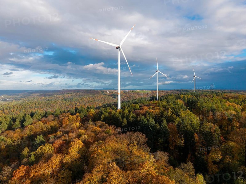 A wind farm rises above an autumnal forest under a cloudy sky, near Schorndorf, Remstal, Rems-Murr-Kreis, Baden-Württemberg, Germany