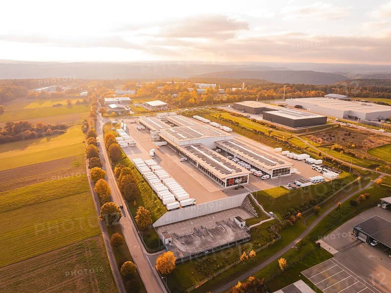 Industrial park with numerous buildings surrounded by green fields and warm skies, Nagold, Black Forest, Germany