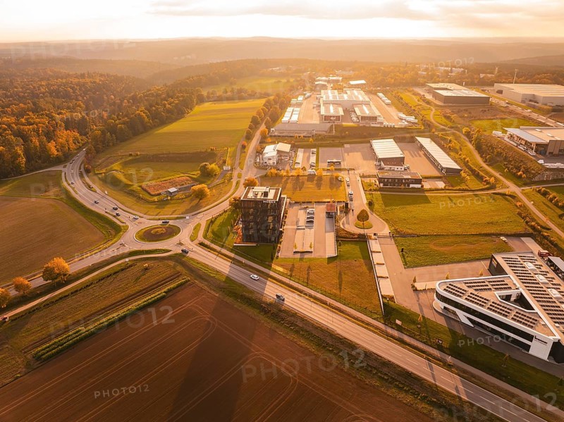 Overview of a large industrial area in the evening light, surrounded by fields and hills, Nagold, Black Forest, Germany