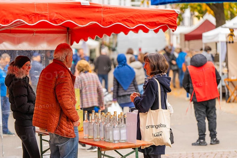 Woman engaged in conversation at a stand with bottles and decorations at a market, traditional fruit market, Sindelfingen, Böblingen district, Germany