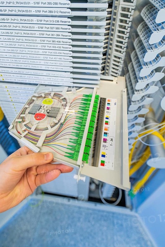 Hand holding a fiber optic cabling module in a technical environment, optical fiber