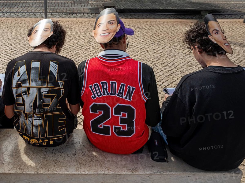Street art, young people with Ronaldo mask on the back of their heads taking part in a school project about drawing, Lisbon, Portugal