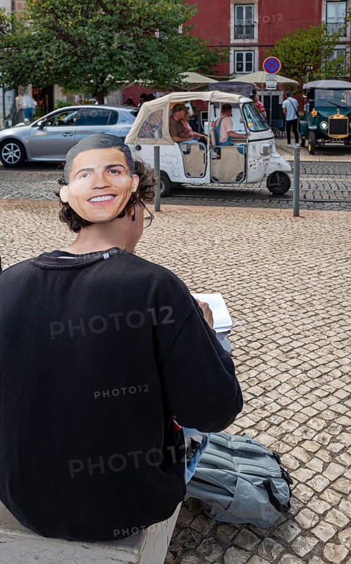 Street art, young people with Ronaldo mask on the back of their heads taking part in a school project about drawing, Lisbon, Portugal