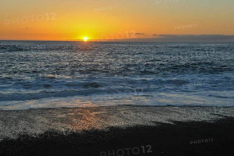 Idyllic sunset on calm calm seas of the eastern Atlantic Atlantic with gentle waves on lava beach, Lanzarote, Canary Islands, Spain