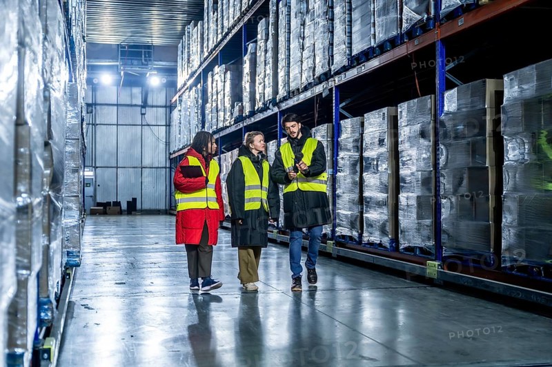 Diverse logistics team is walking and discussing inventory management within a modern cold storage warehouse, ensuring efficient operations for frozen goods