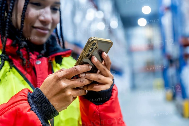 Logistics professional checking inventory with a mobile phone, optimizing cold chain operations and managing supply in a modern frozen warehouse environment