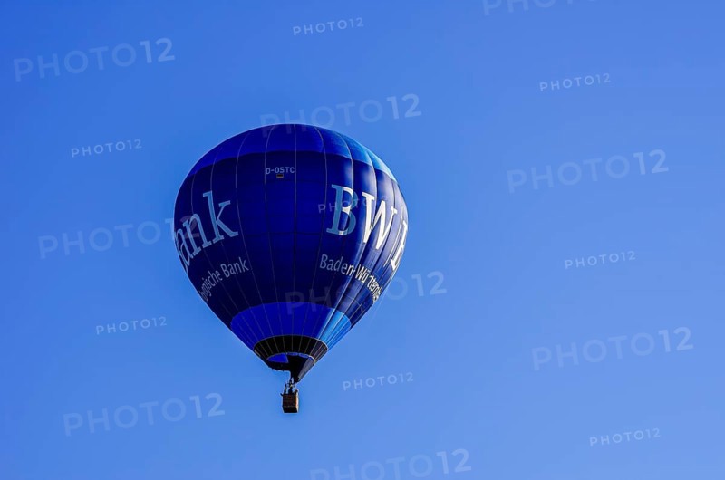 A hot air balloon, registration D-OSTC, rises into the air as part of an air show at the Rossfeld Air Sports Association's Flying Festival on Rossfeld in Metzingen-Glems, Baden-Württemberg, Germany, for editorial use only
