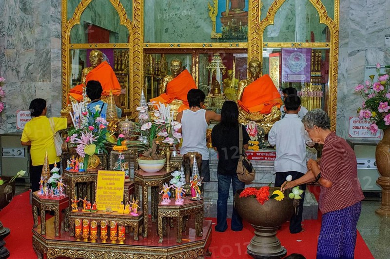 Buddhist believers Buddhists pray making offerings to statues of Buddhist monks covered with gold leaf at Wat Chalong Monastery, Wat Chaithararam, Phuket Island, Phuket Province, Thailand