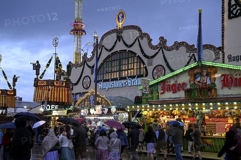 Oktoberfest visitors with umbrellas, rainy meadows, Augustiner festival tent, Munich, Bavaria, Germany