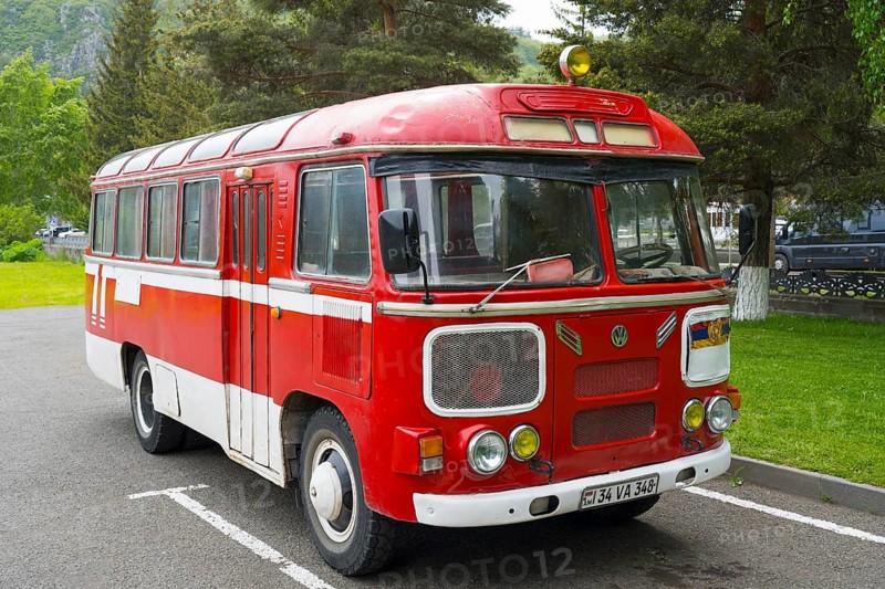 Red retro bus in a parking lot surrounded by trees and green nature, PAZ-672, minibus from Soviet manufacturer Pavlovsky, Jermuk, Jermuk, Vayots Dzor province, Armenia