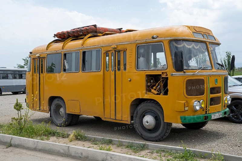 Vintage yellow bus on a road surrounded by a meadow, under cloudy sky, PAZ-672, minibus from Soviet manufacturer Pavlovsky, gas drive, Khor Virap, Ararat province, Armenia