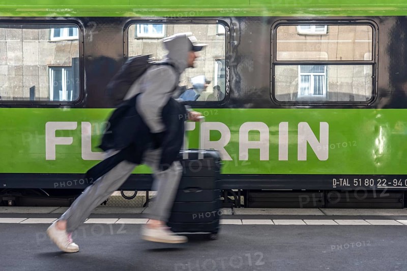 Flixtrain train on track 2 in Essen main station, passenger runs with luggage to reach his train, North Rhine-Westphalia, Germany