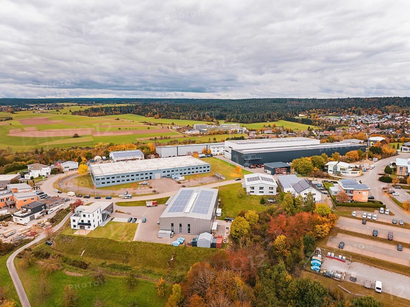 Industrial buildings surrounded by fields and trees in autumn colors under cloudy sky, Dornstetten, Freudenstadt district, Germany
